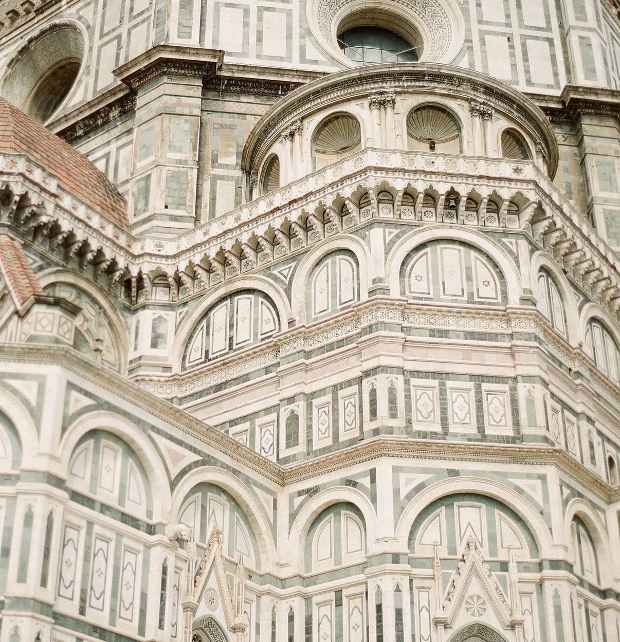 A close view of an ornate cathedral façade in patterned green-and-white marble, with tiered arches, columns, and fine architectural detailing.